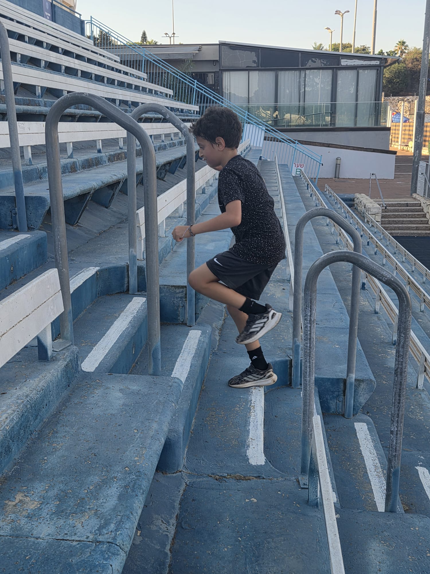נער מתאמן על עליות מדרגות ביציע האצטדיון לחיזוק כוח רגליים