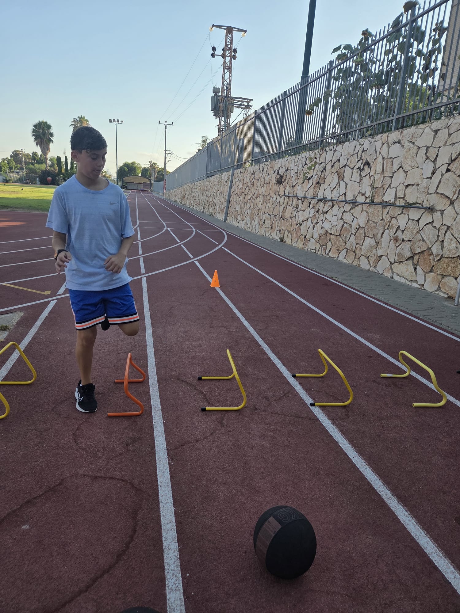 נער מתאמן על מסלול אתלטיקה עם משוכות זריזות ברמת השרון